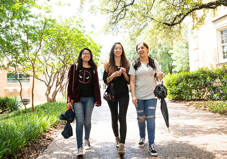Three female college students walking outside campus.